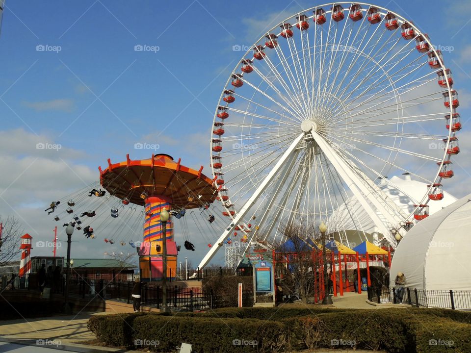 Red everywhere. Amusement park with a Ferris wheel and exciting rides and lots of people having fun