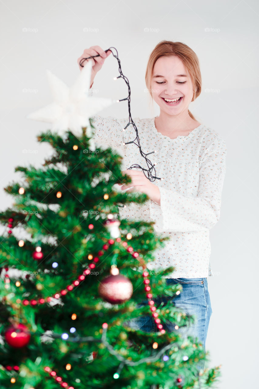 Smiling teenage girl decorating christmas tree