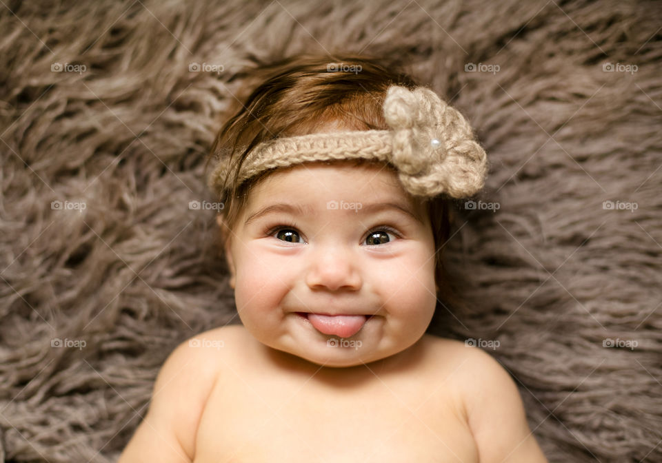 Baby girl with woolen hair band lying on carpet