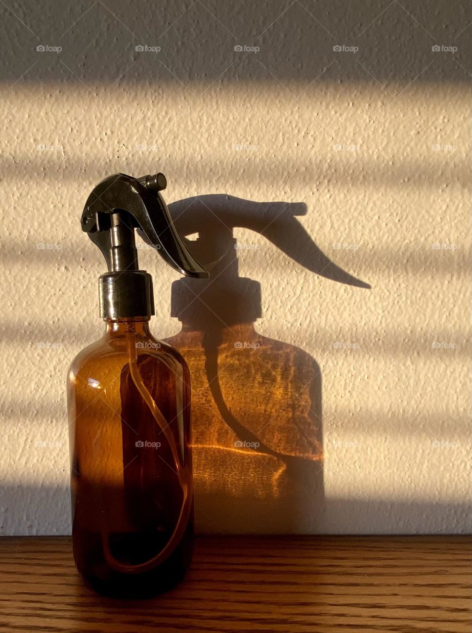 Brown glass spray bottle with window blind shadow
