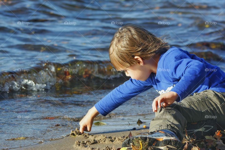 Kid writing on sand with his finger. Kid writing on sand with his finger