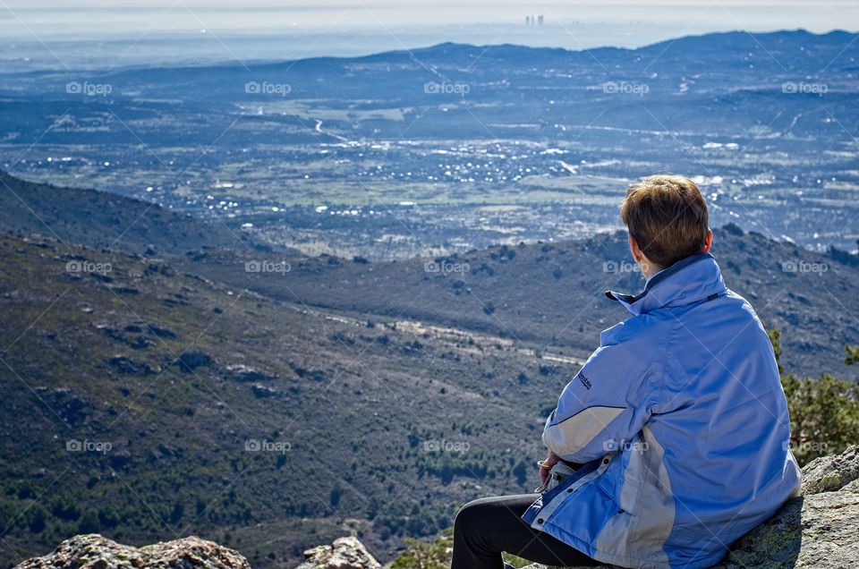 Rear view of a woman sitting on top of a hill 