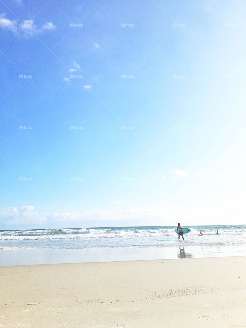 A surfer carries his surfboard into the ocean for a day of surfing at Ponce Inlet Beach.