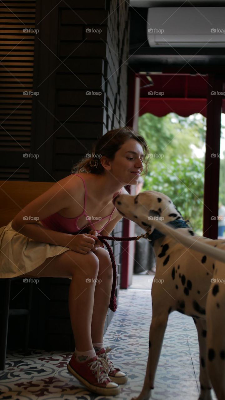 Girl with dog Dalmatian in cafe