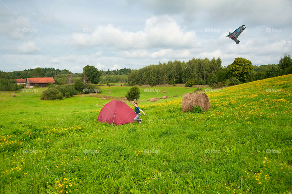 Little girl flying a kite in countryside.