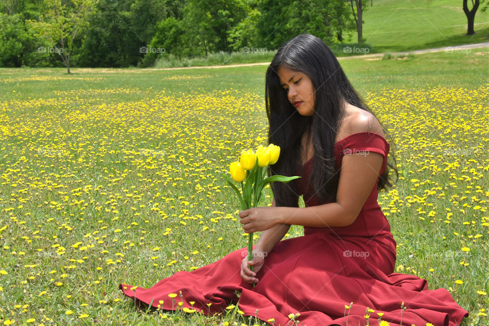 Love Color, girl in red dress sitting in a field of buttercups holding yellow tulips 