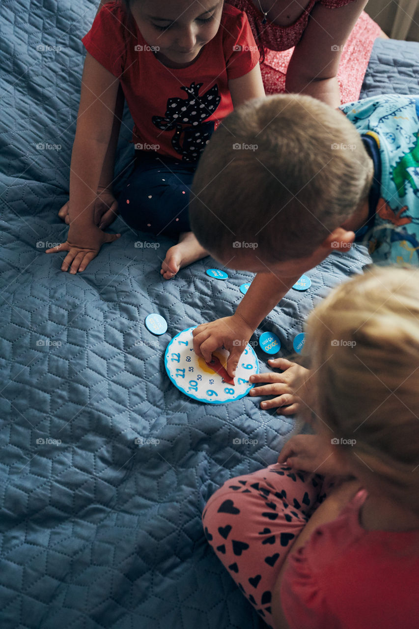 Kids learning how to tell time from clock and set the hands in the correct position. Teaching preschoolers tell time. Candid people, real moments, authentic situations