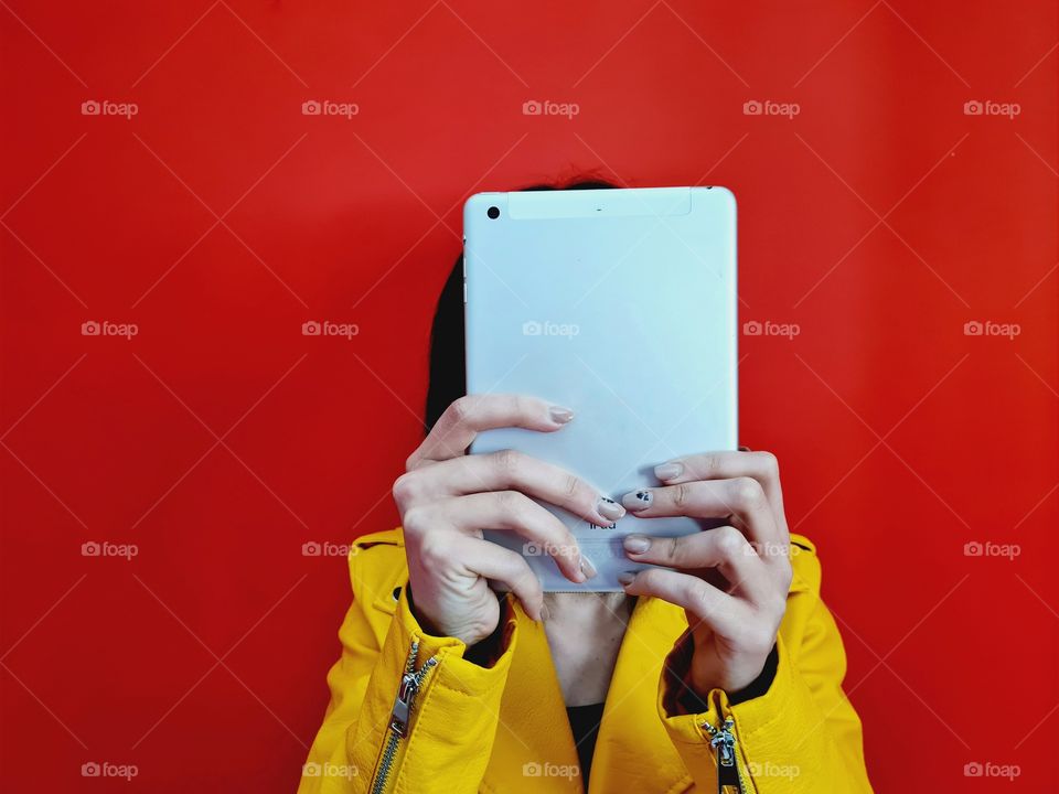 girl uses tablet in front of a red wall