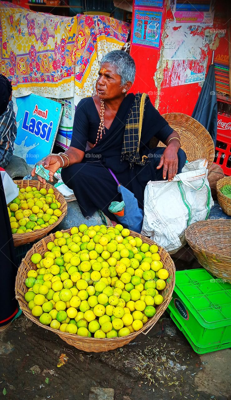 indian old lady selling lemon in market