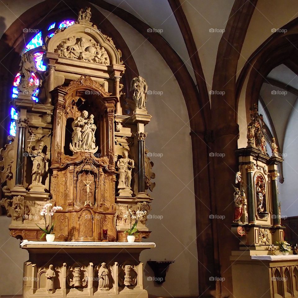 The interior of an old European church with ornate and finely detailed alters and statues. 