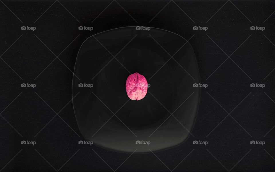 Purple walnut on a black in a dark room, viewed from top 