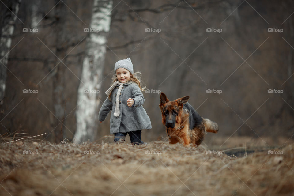Little girl with German shepherd young male dog walking outdoor at spring day