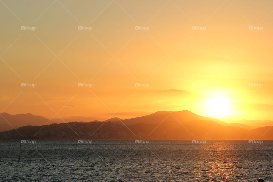 Sunset at sea with hills in the background. In Florianopolis Brazil