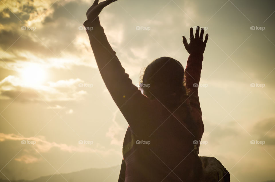 Beautiful fashionable woman enjoying holiday in sunset sun of orange sky background, raise hands up in air close up, back view Success in life concept