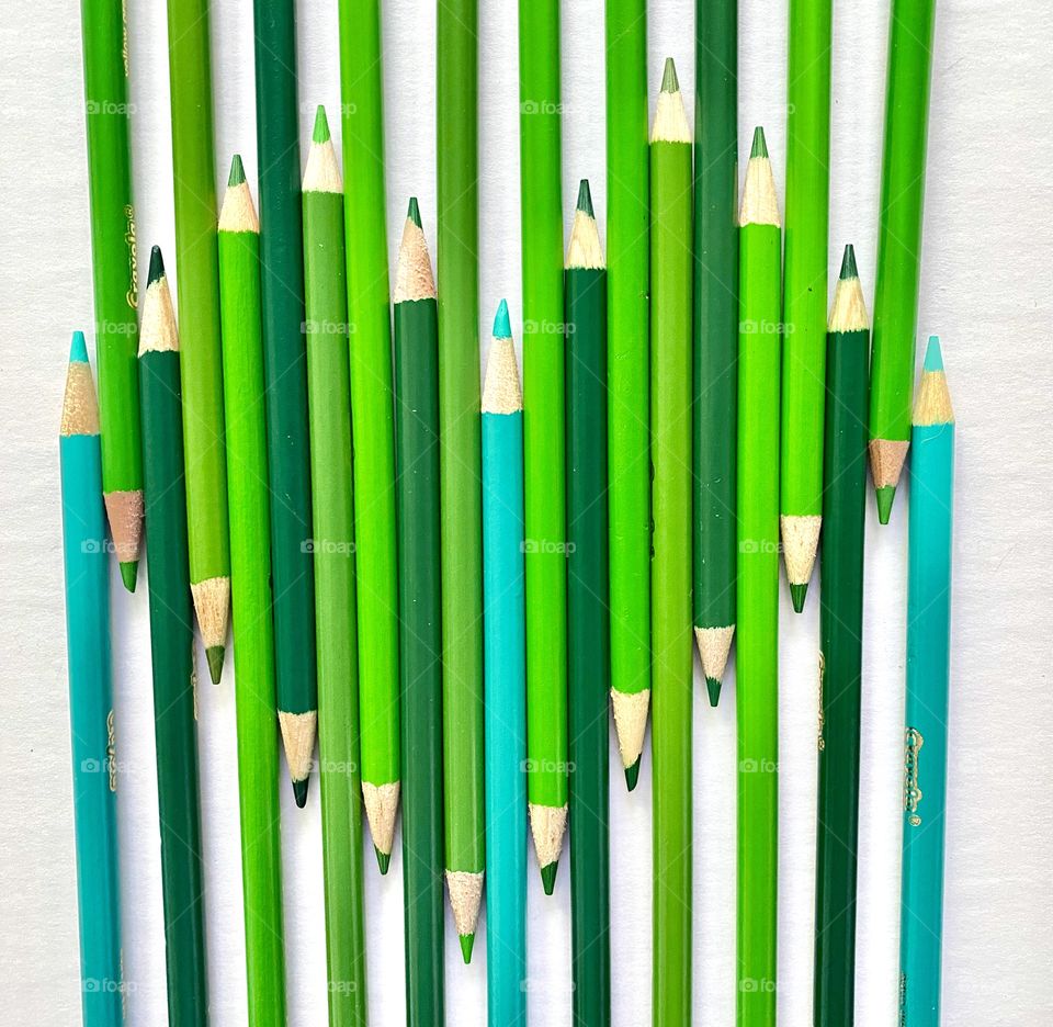 Green colored pencils creating the shape of a heart