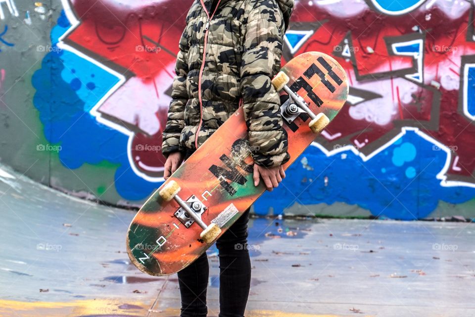 Girl with skateboard under her arm on the skate park 