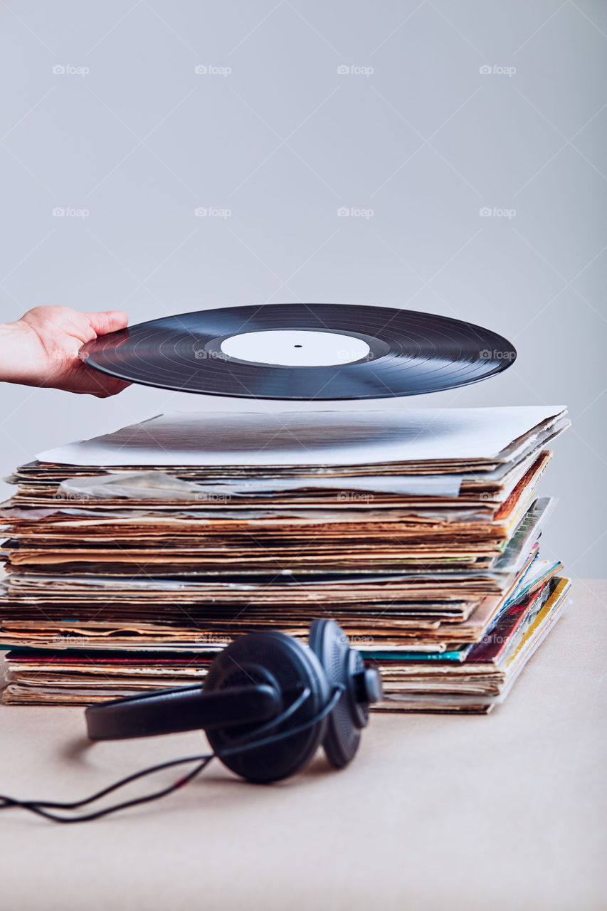 Woman taking vinyl from stack of many black vinyl records, headphones put at the front of vinyls. Copy space for text. Candid people, real moments, authentic situations