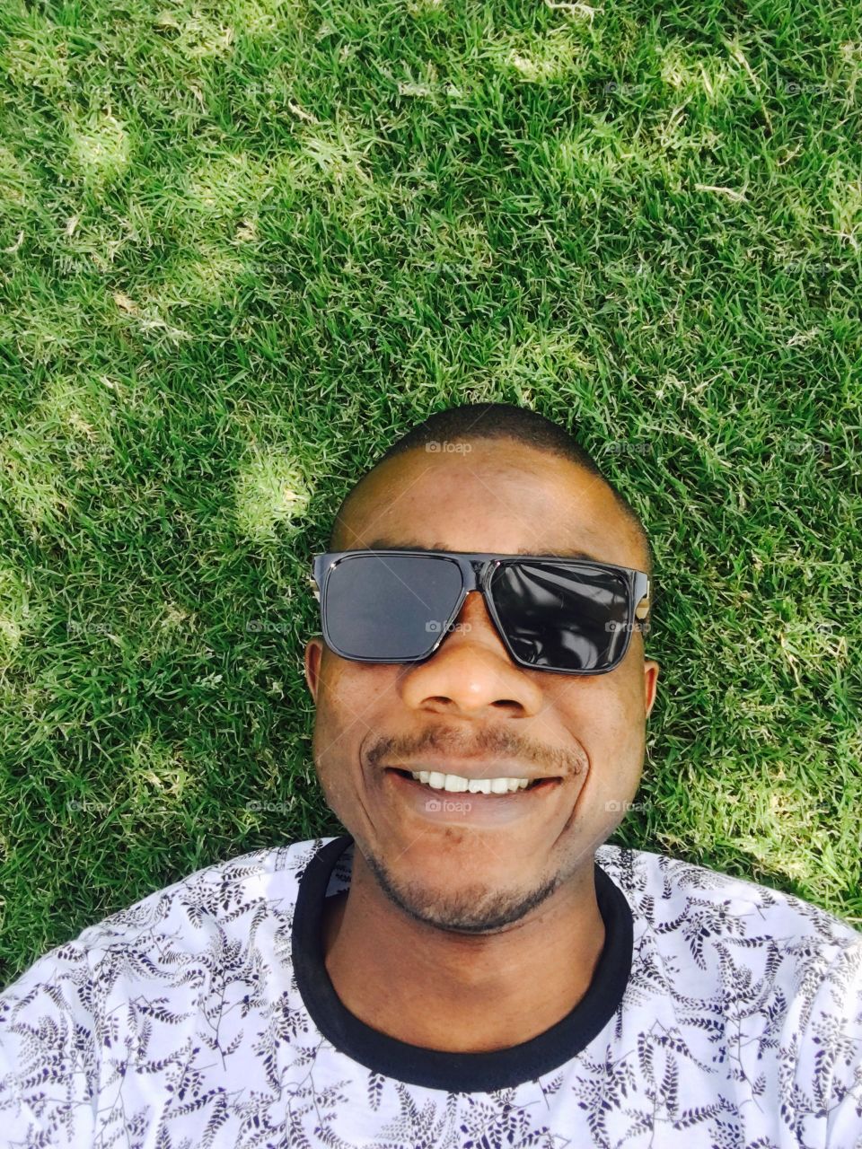 Man lying down on grass with glasses 