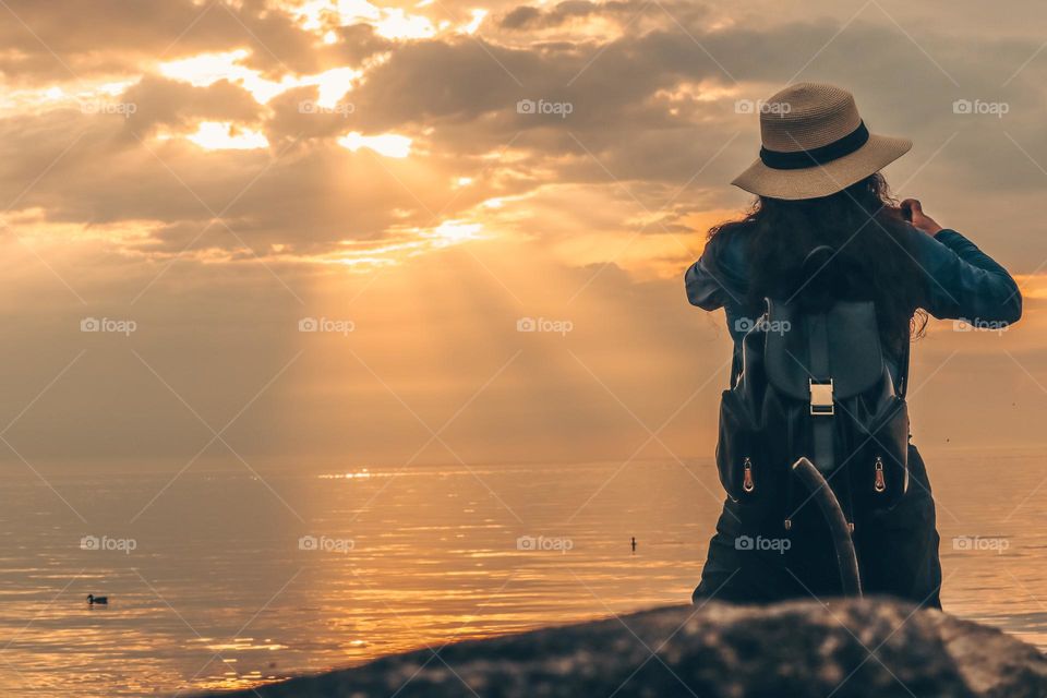 Woman is photographing beautiful sunrise on a lake