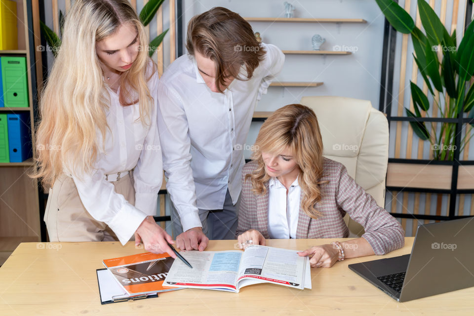 team of Caucasian young people discussing textbooks in college classroom