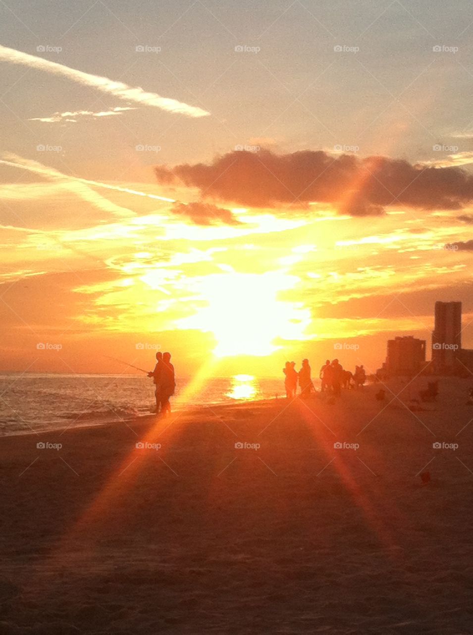 Sunset fishing silhouettes on the beach.