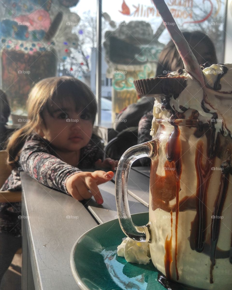 Little girl with ice cream in glass mug on table