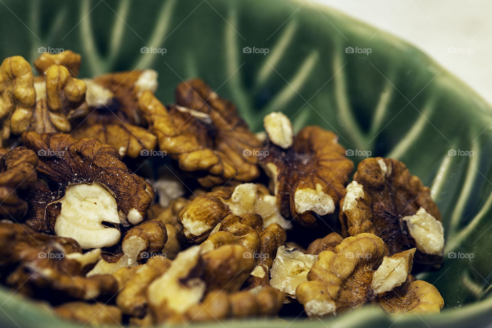 A beautiful textured green bowl full of delicious pecan nuts