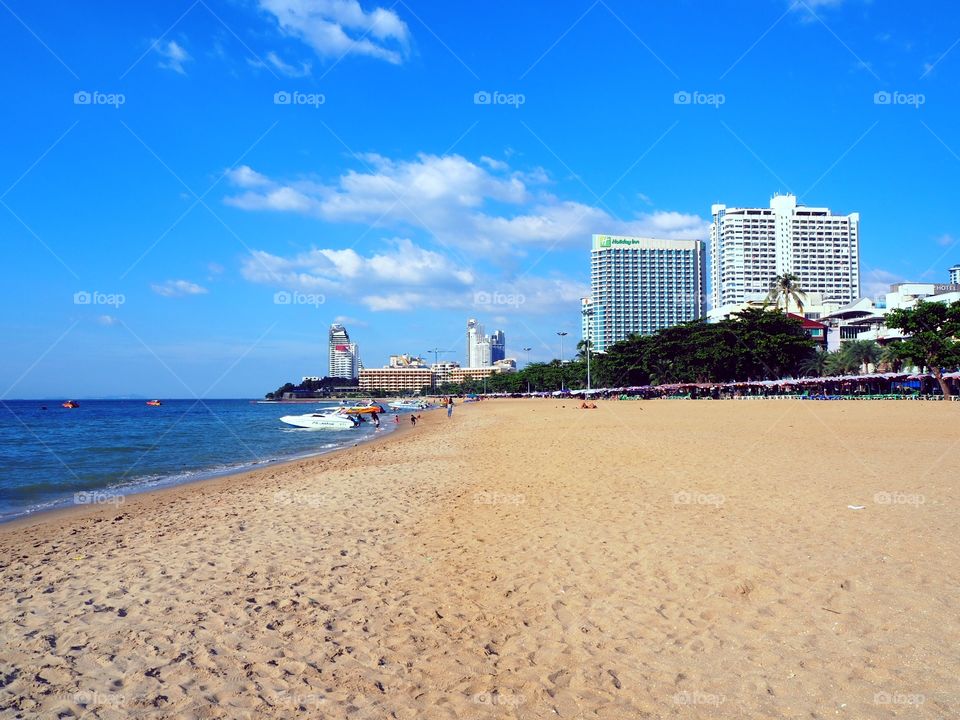 Small boat anchored in the shoreline of the beach with buildings on it's background.