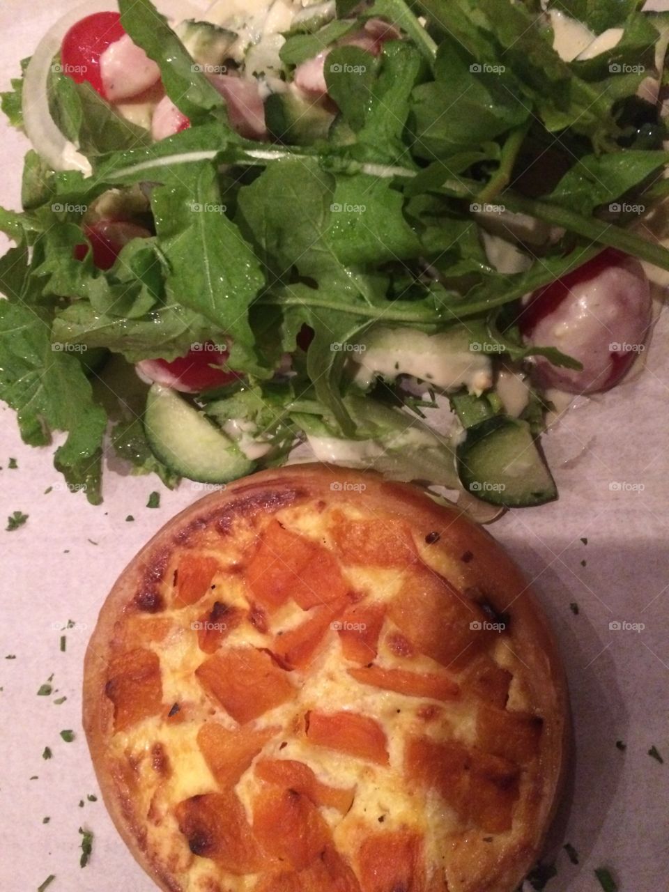 Butternut and feta quiche served with side salad as a light lunch or supper in a restaurant 