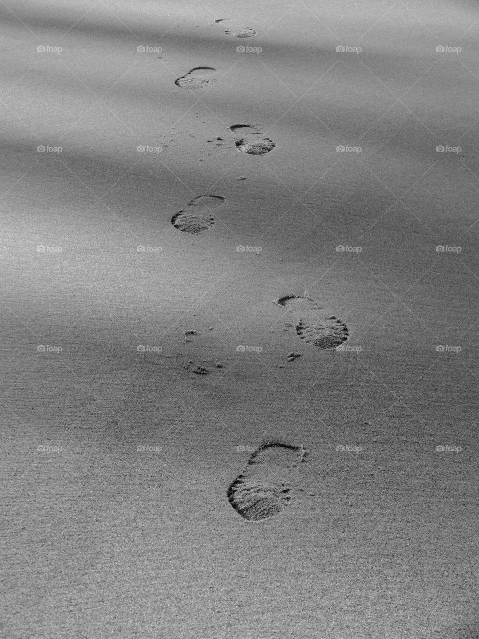 Black and white shot of shoe prints in sand at the beach in Rewal, Poland.