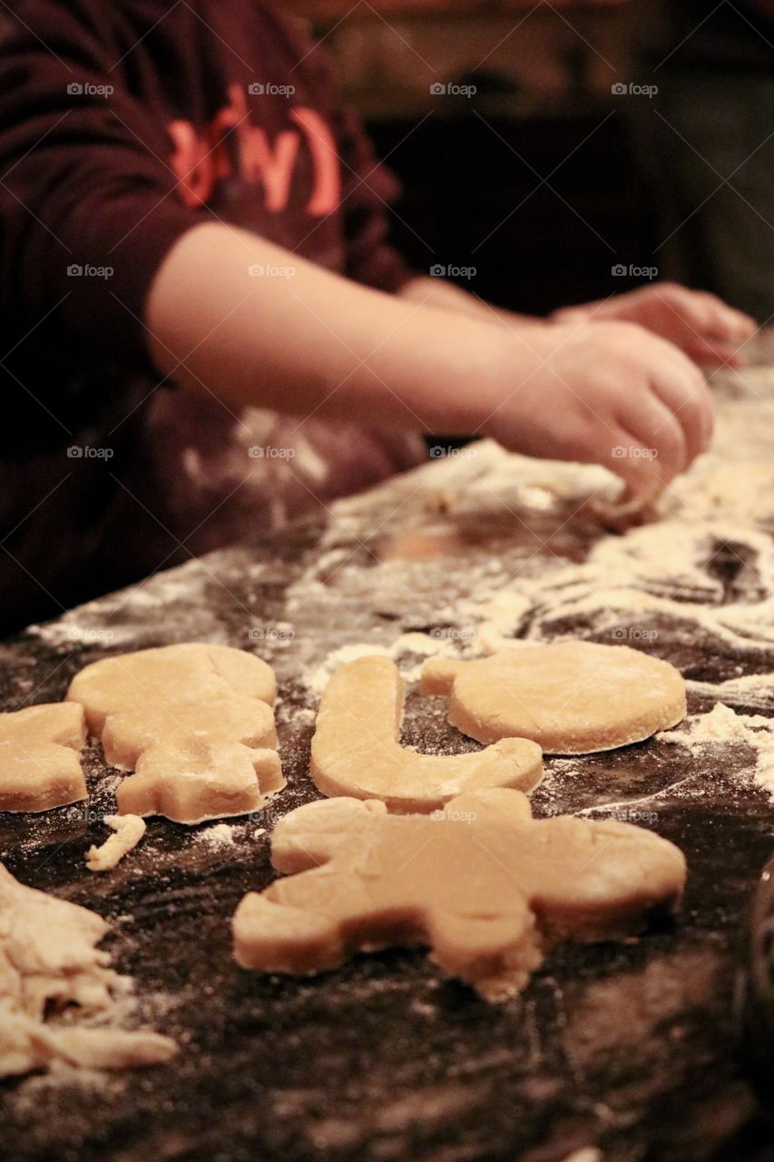 Baby making cutout cookies on the kitchen counter.