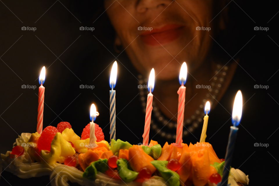 colorful birthday cake with burning candles and woman dark background