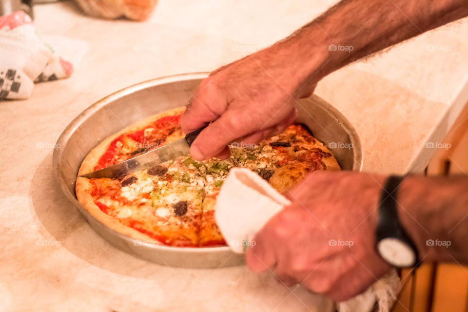 Men cutting pizza slices