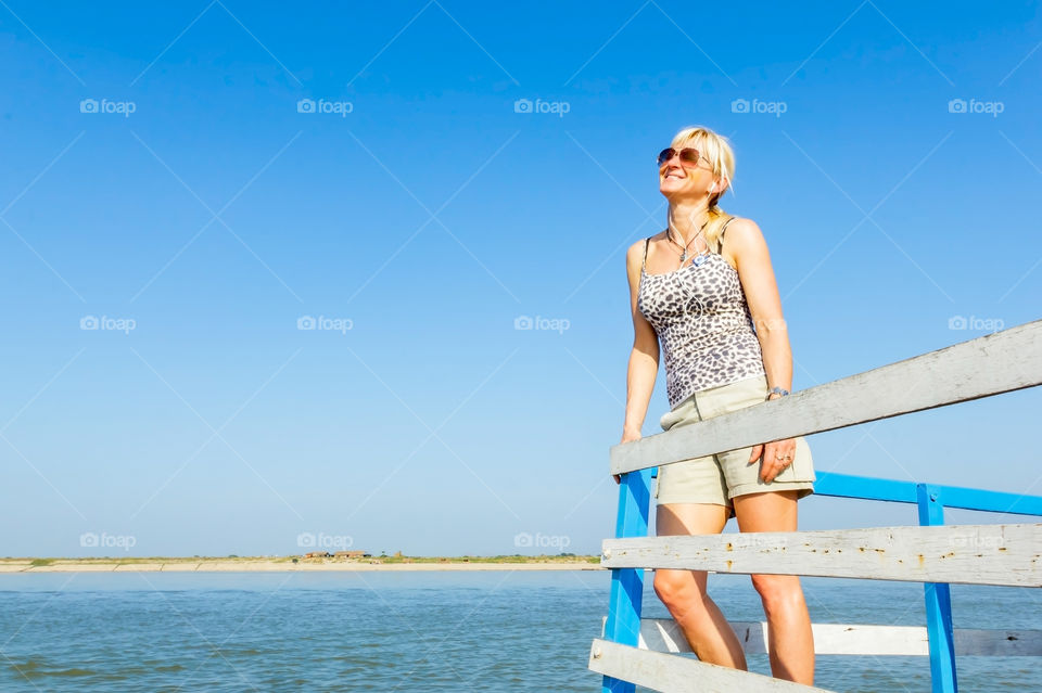 Woman standing near wooden railing in sea