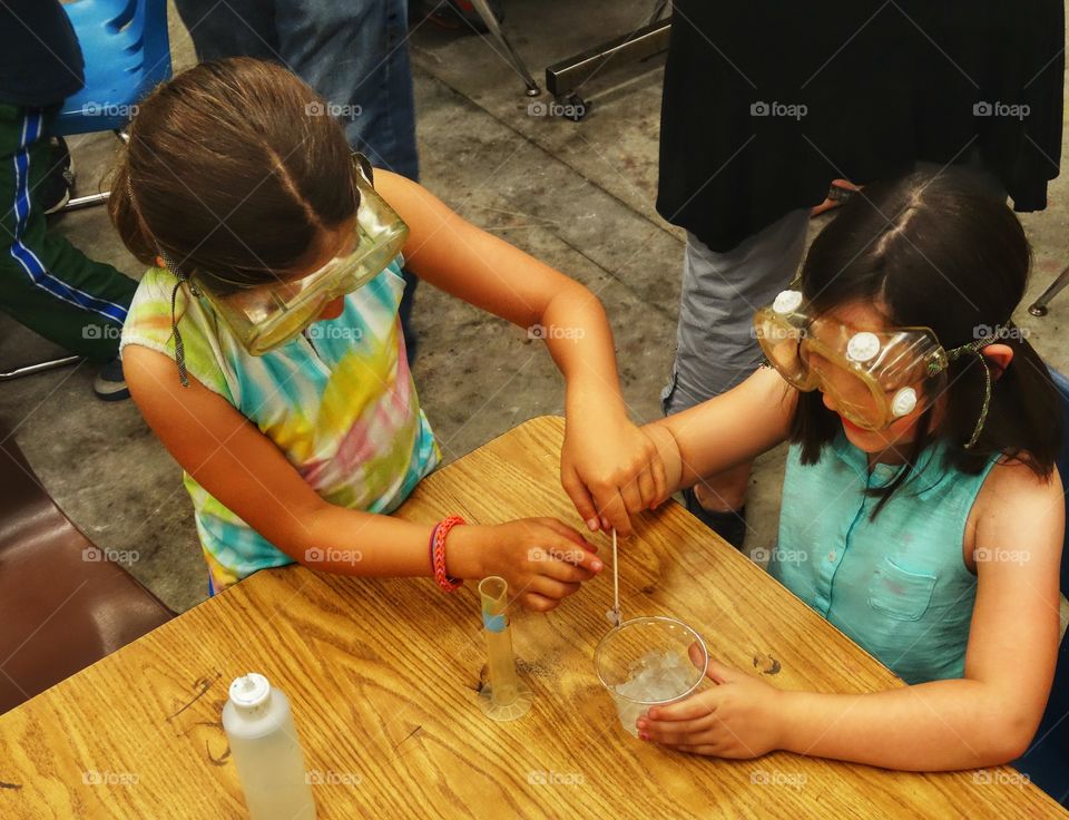 Desk From Above. Girls Performing A School Chemistry Experiment
