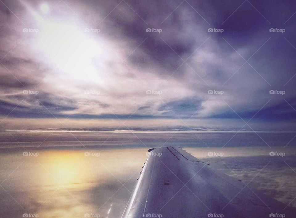 high altitude view while flying, sun's reflection on water