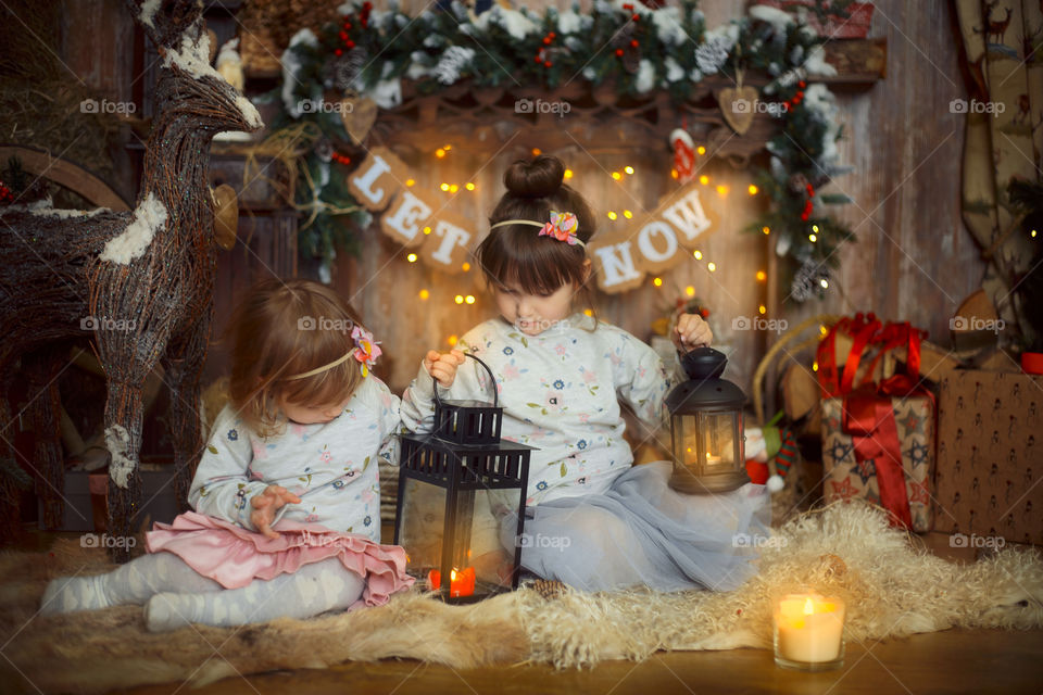 Little sisters near fireplace at Christmas Eve 