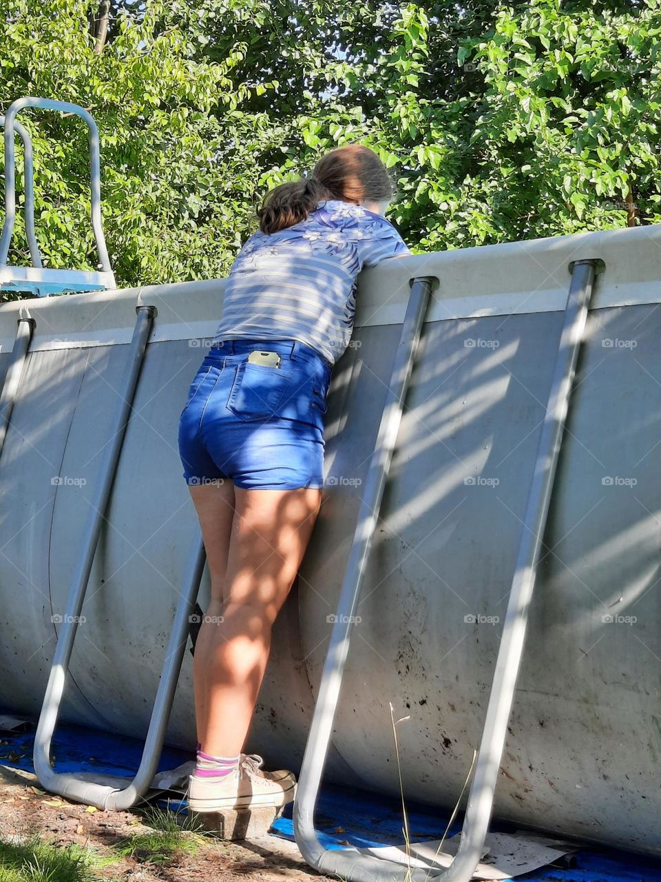 girl in summer outfit looking down in swimming pool