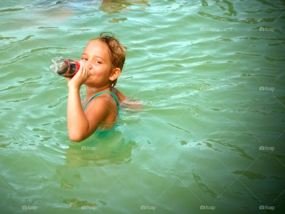 Girl in the water with a Coke