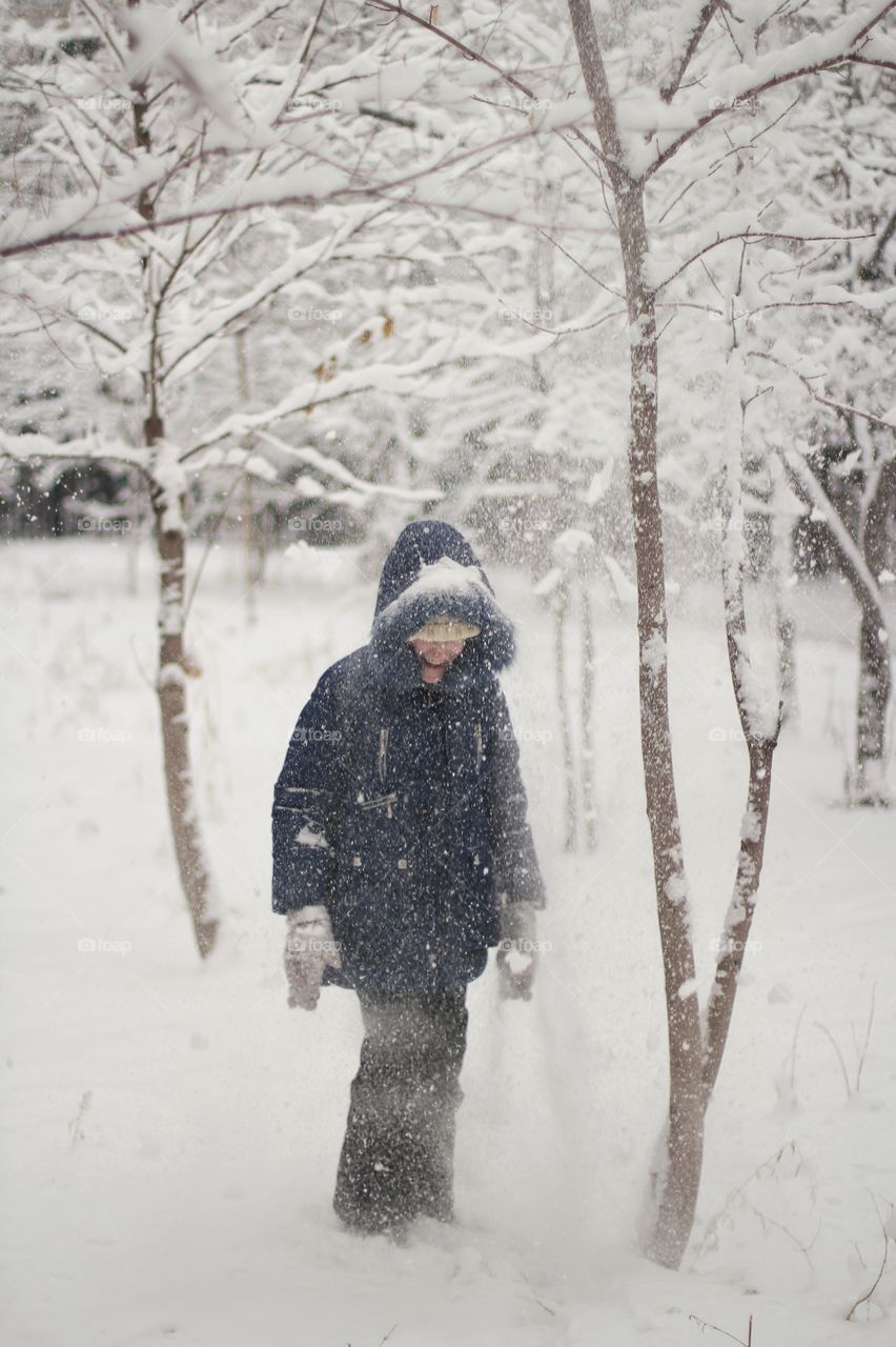 Girl laughing under snow falling from a tree