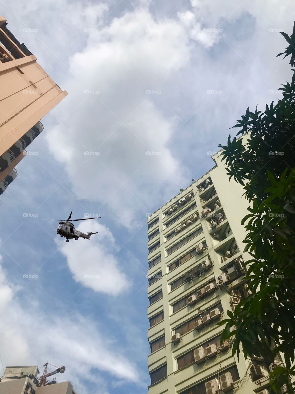 Helicopter flying above sky vehicle transportation cityscape town building tree 