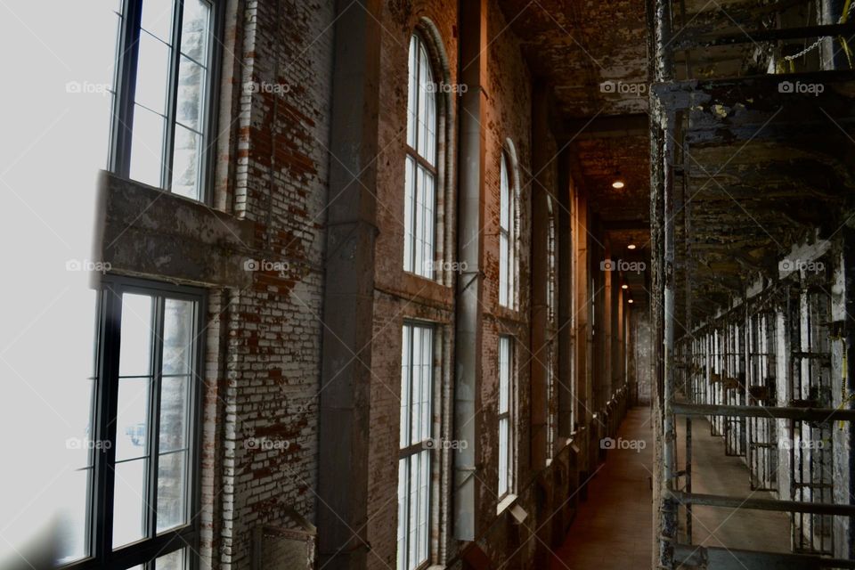 A long row of arched windows with rusty frames within a decaying brick wall