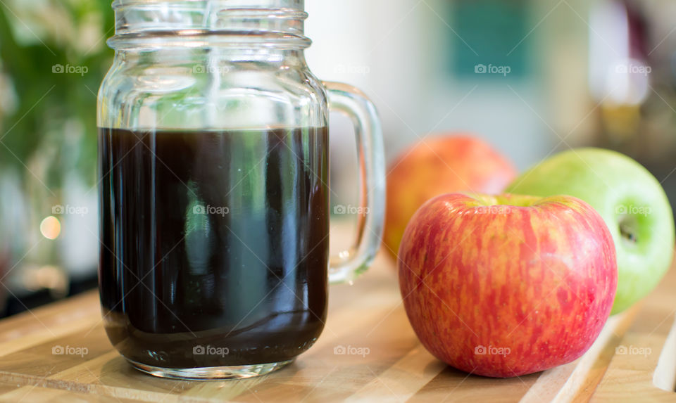 Fresh different colored apples next to coffee mug in kitchen on wood table conceptual healthy start to the day breakfast photography