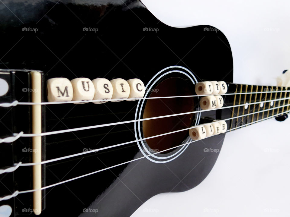 Letters of beads on a black ukulele. Letters of beads on a black ukulele