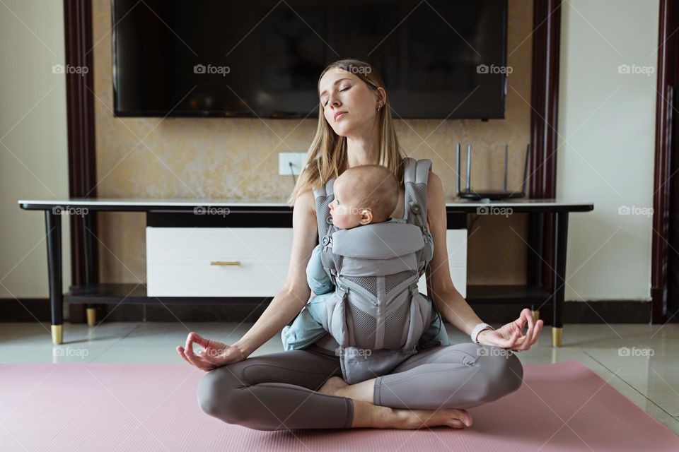 Young mother meditating with baby at home