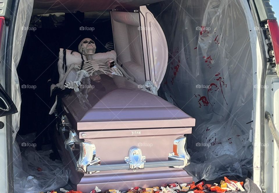 A photo of a plastic skeleton sitting in a coffin.