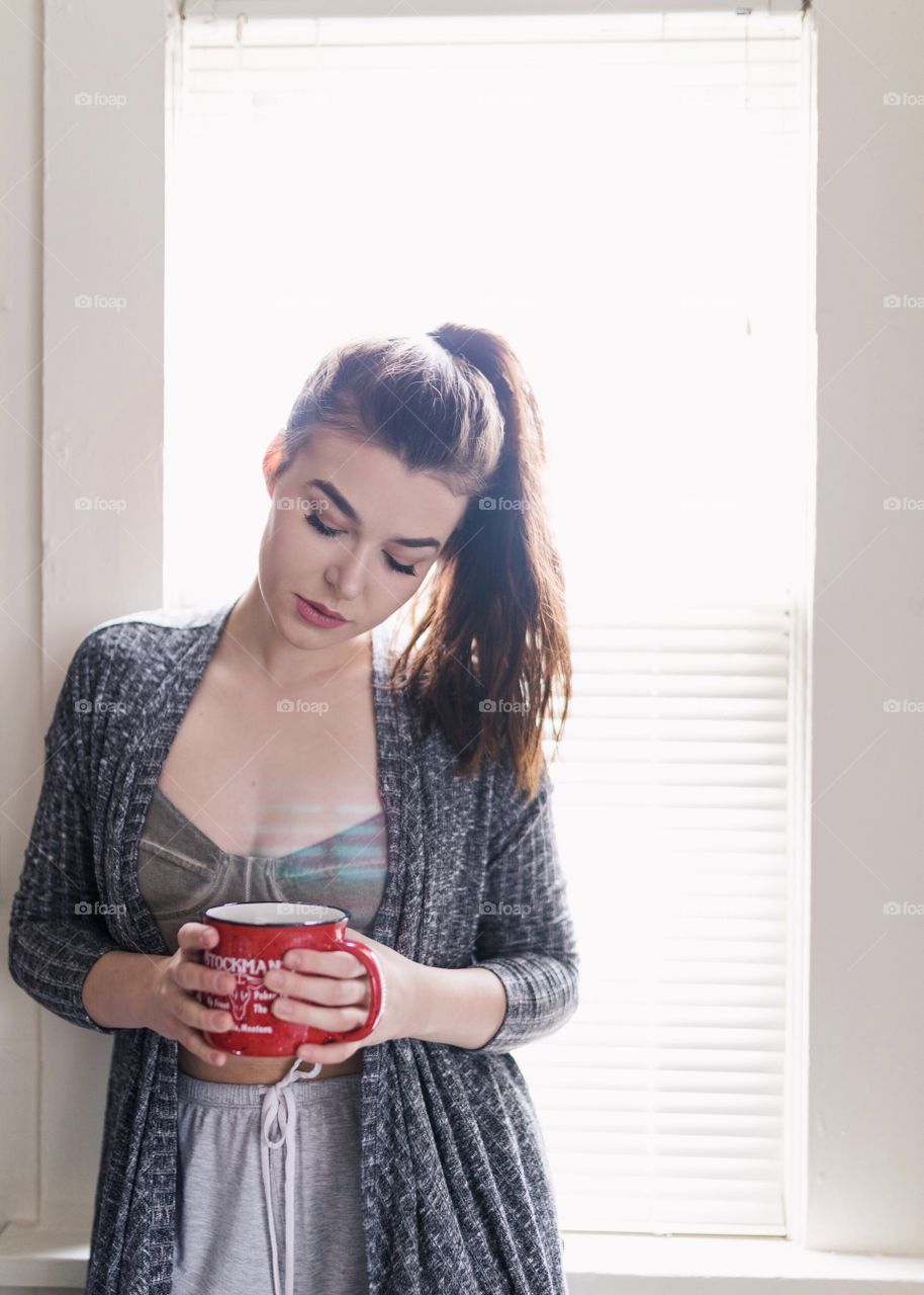 Brunette girl in her pajamas drinking a cup of tea before school in the morning. 