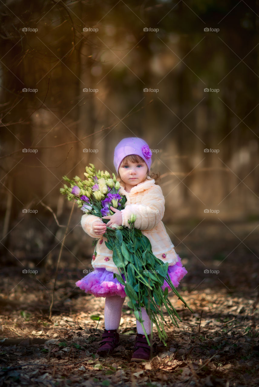 Little girl with bouquet of flowers at spring day