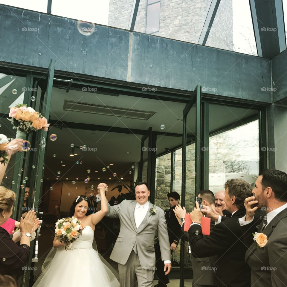 My cousin’s wedding photo in New York. Newlyweds in love. Them walking out like we finally did it with everyone congratulating them. Very light hearted and whimsical with bubbles in the air.