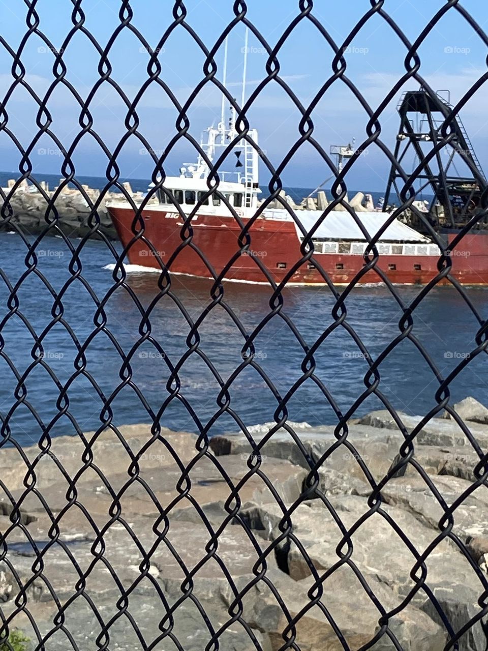 A red fishing boat named “Big Red” heads into the Manasquan Inlet on its way back from the ocean with its catch. I shot this through the fence on the north end of the Point Pleasant Beach boardwalk. It’s a great place to watch the boats go by.